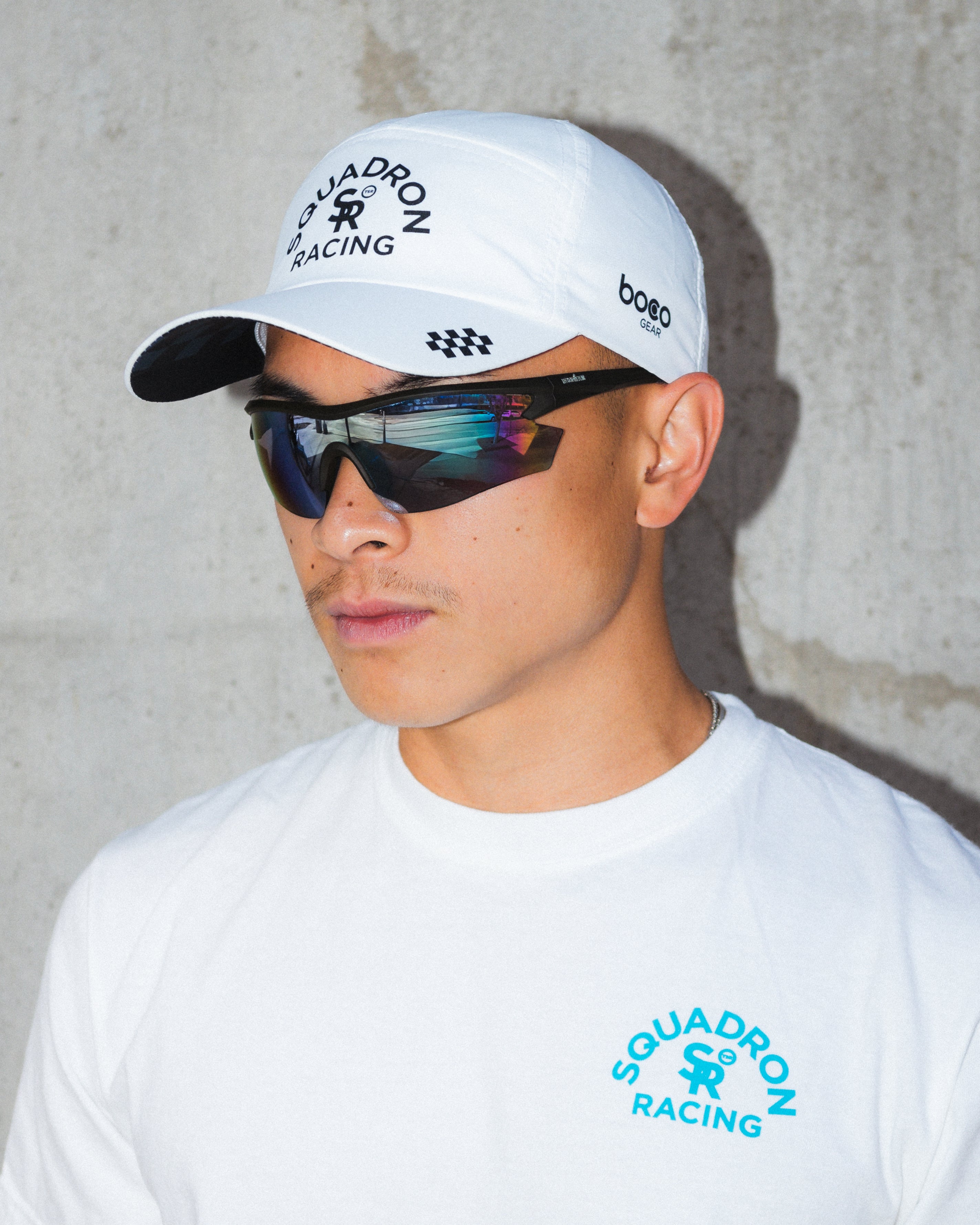 Athlete in frame  wearing a white squadron racing white hat and t shirt. 