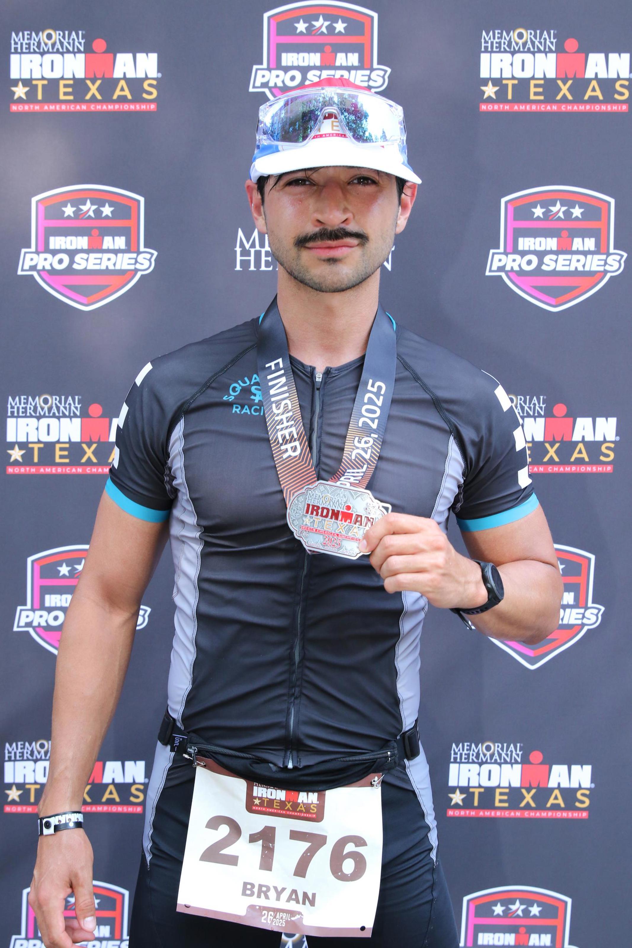 Squadron Racing triathlete finishing an ironman race holding the finisher medal.
